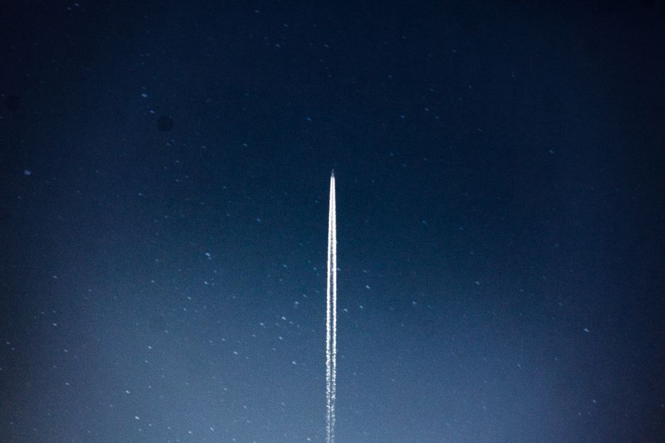 A rocket streaking through a starry night sky, leaving a bright trail.