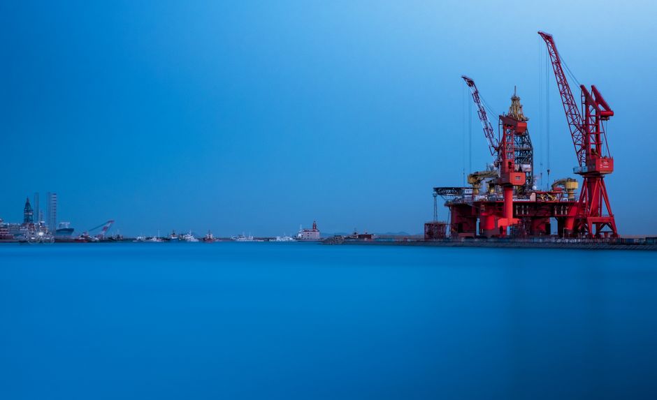 An offshore oil platform and cranes at a maritime energy facility, illustrating the infrastructure exposed to shipping-route disruption.