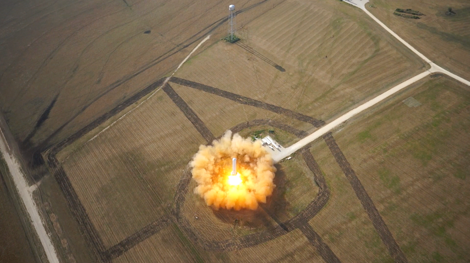 Rocket lifting off from a launchpad in open terrain
