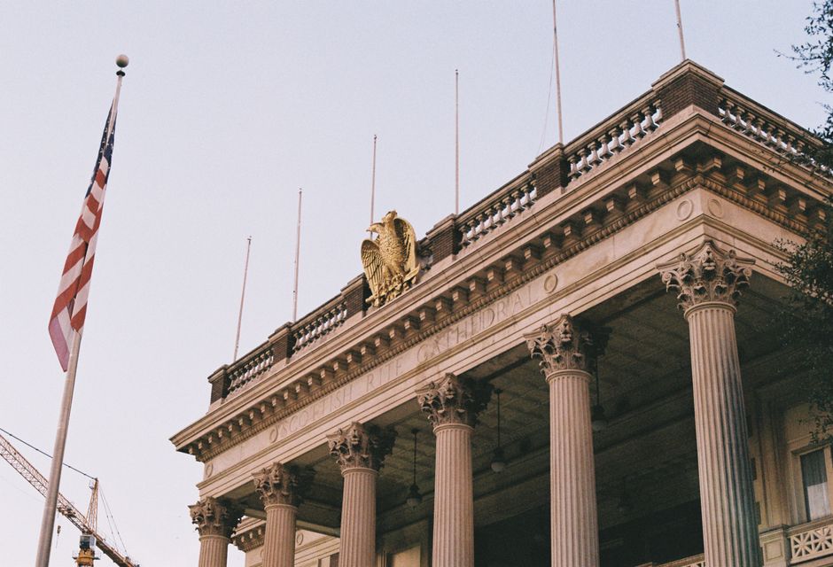 Neoclassical building facade with columns, an American flag, and an eagle crest