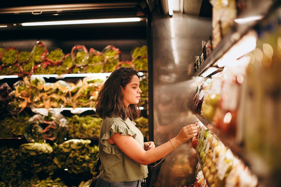 A shopper selecting fresh produce in a supermarket aisle