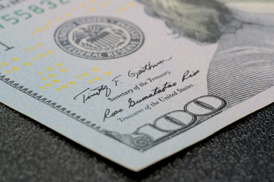 A close-up of a US hundred-dollar bill showing intricate security features, representing the inflation and rate dynamics shaping market response to geopolitical shocks.