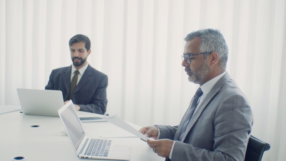 Professional reviewing corporate documents and financial information at a desk.