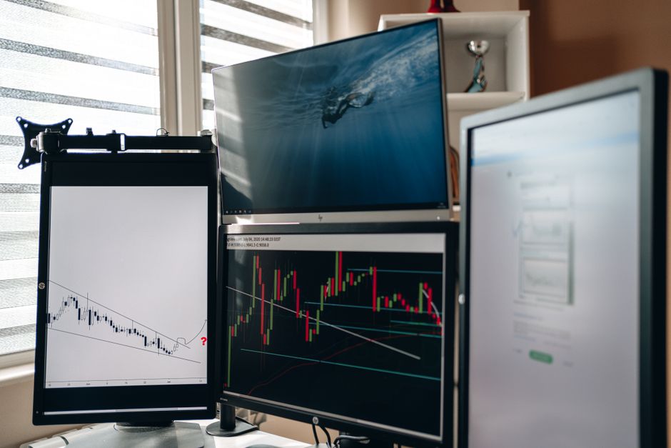 Multiple monitors displaying financial trading charts and market data in a trading workstation setup.