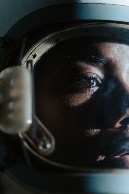 Detailed image of an astronaut's face through a helmet with light reflections.