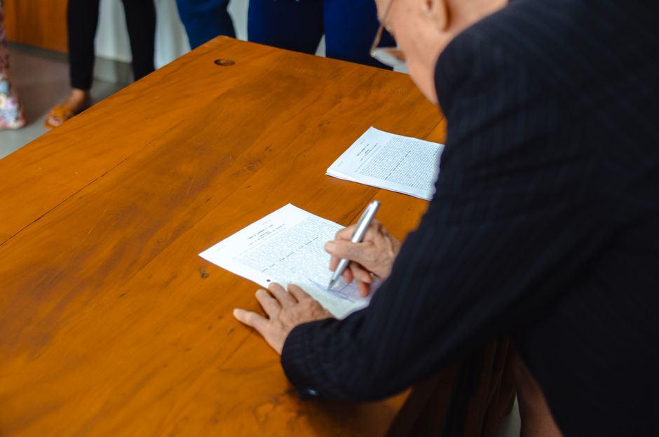 A close-up of a businessman signing official documents at a wooden desk