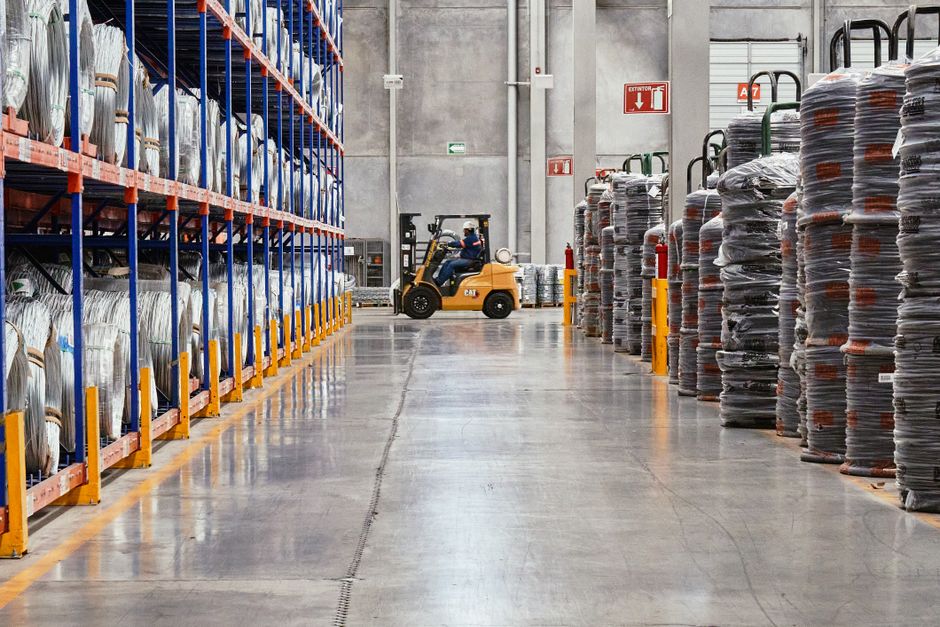 A forklift operating in an industrial warehouse with stacked goods.