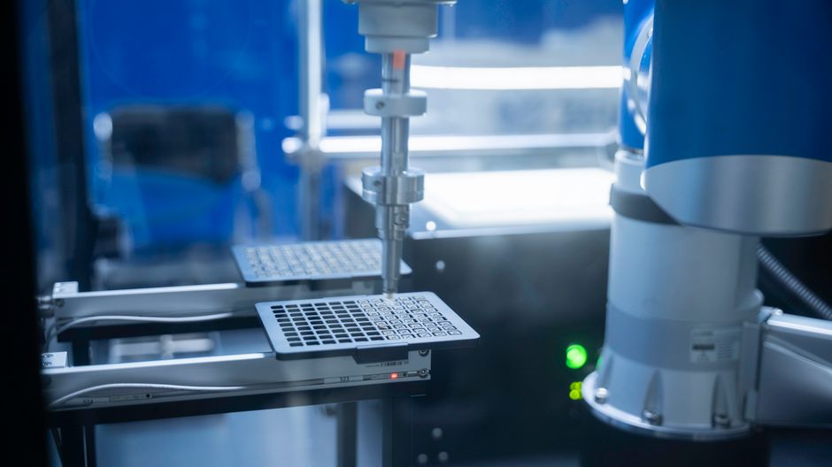 Close-up of an automated robotic arm in a precision laboratory, representing the advanced manufacturing behind semiconductor and AI infrastructure.