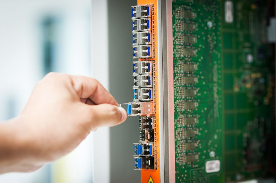 Engineer connecting a cable into a network server port in a data center room