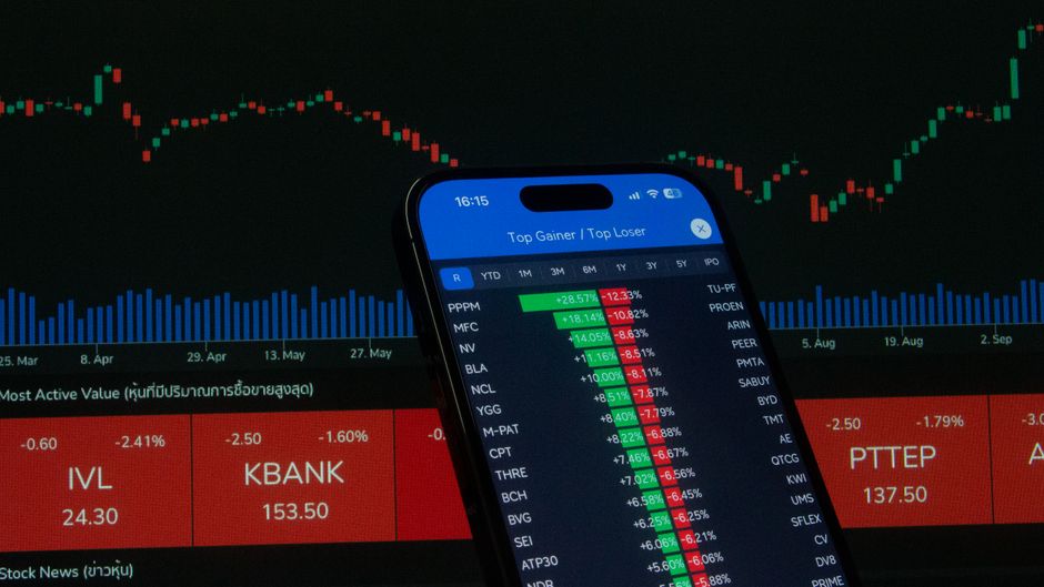 Smartphone displaying stock market data in front of a financial chart, representing the market’s AI-led move