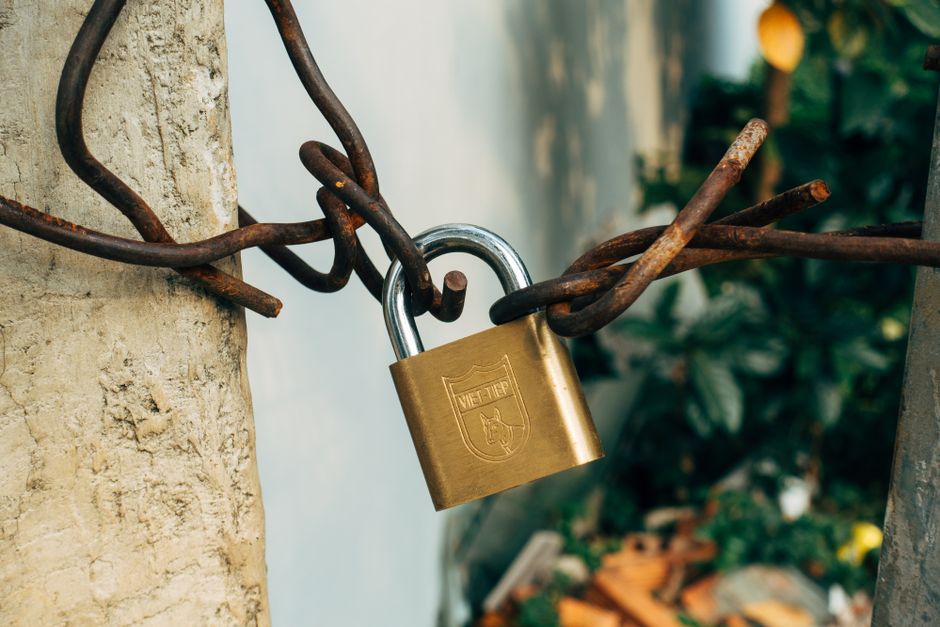 A brass padlock securing a metal wire on a concrete post, symbolizing the lockup restrictions that expire on SpaceX shares beginning August 6.