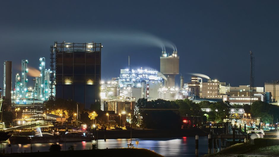 Illuminated industrial facilities and city infrastructure at night represent the power-intensive build-out behind AI services.