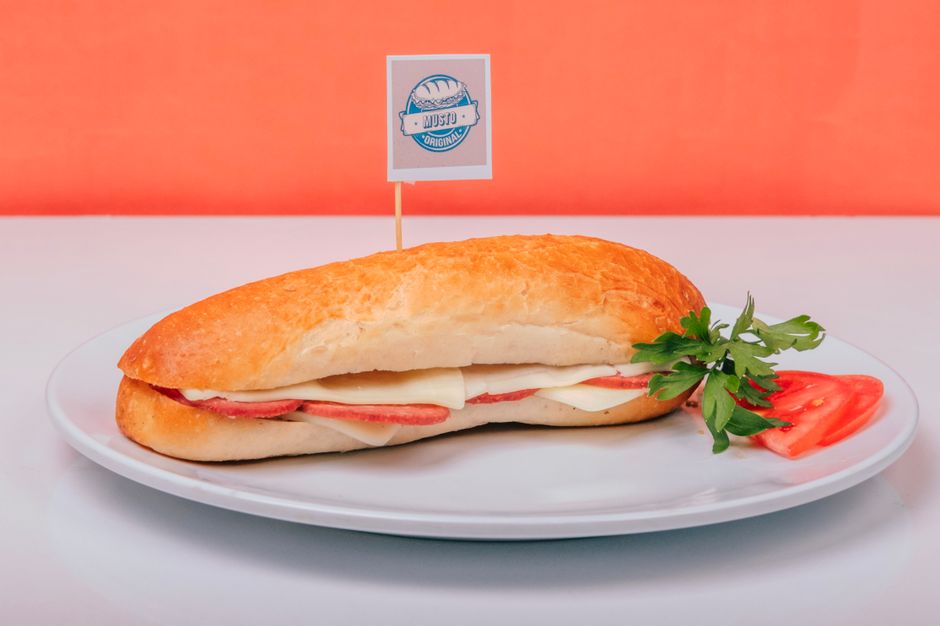 A ham and cheese sandwich on a plate, garnished with tomato and parsley