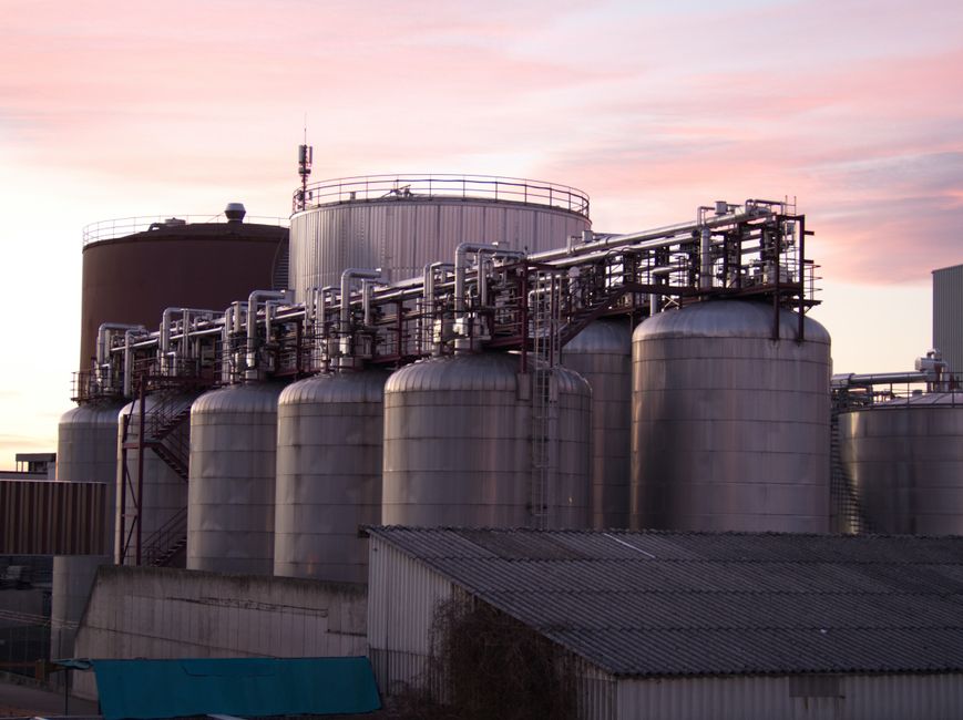 Industrial refinery with stainless steel storage tanks at sunset