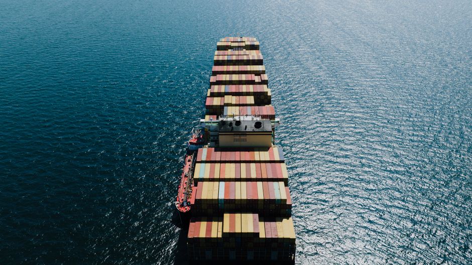 Loaded cargo ship sailing through the sea viewed from above, illustrating maritime trade through strategic chokepoints.