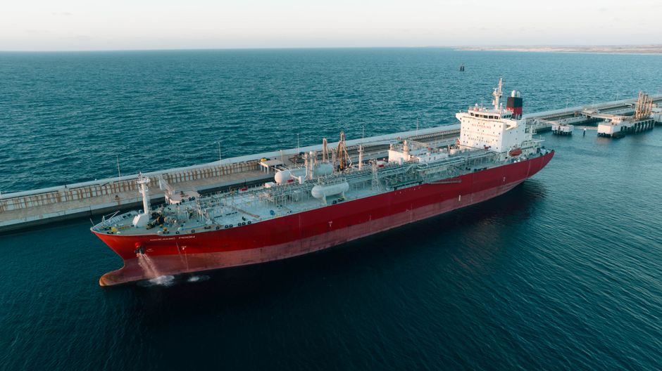 Aerial view of a cargo ship at a coastal port, representing the maritime chokepoint at the center of the market risk.