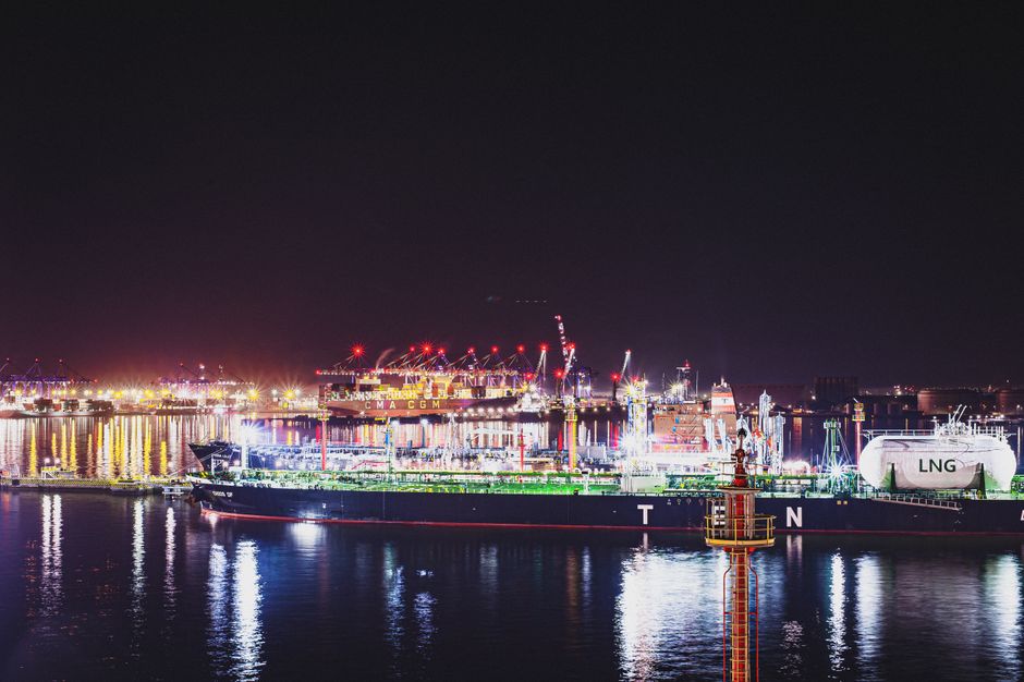 An illuminated cargo port handling ships and cranes at night.