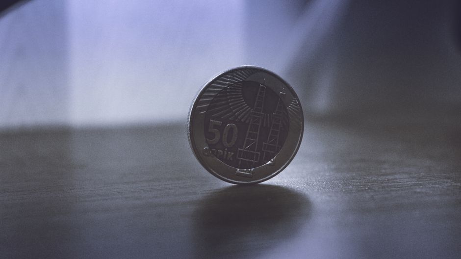 A gray coin on a wooden surface, symbolizing the market’s focus on money, rates, and the cost of capital.