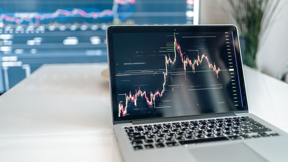 A laptop displaying market charts and financial data.