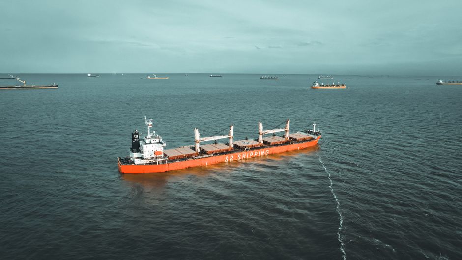 Drone view of a cargo ship navigating the open ocean, showcasing maritime transport.