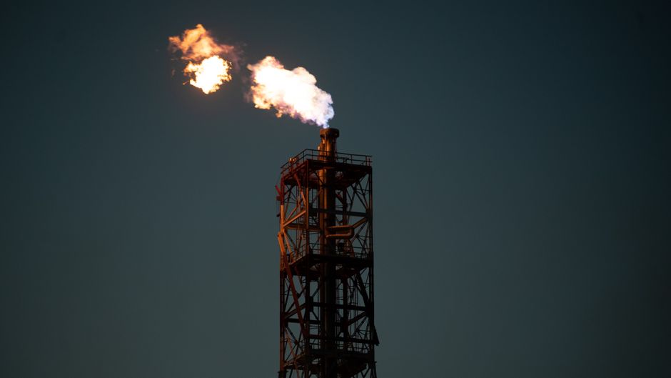 Industrial flare stack with flame against a dark sky