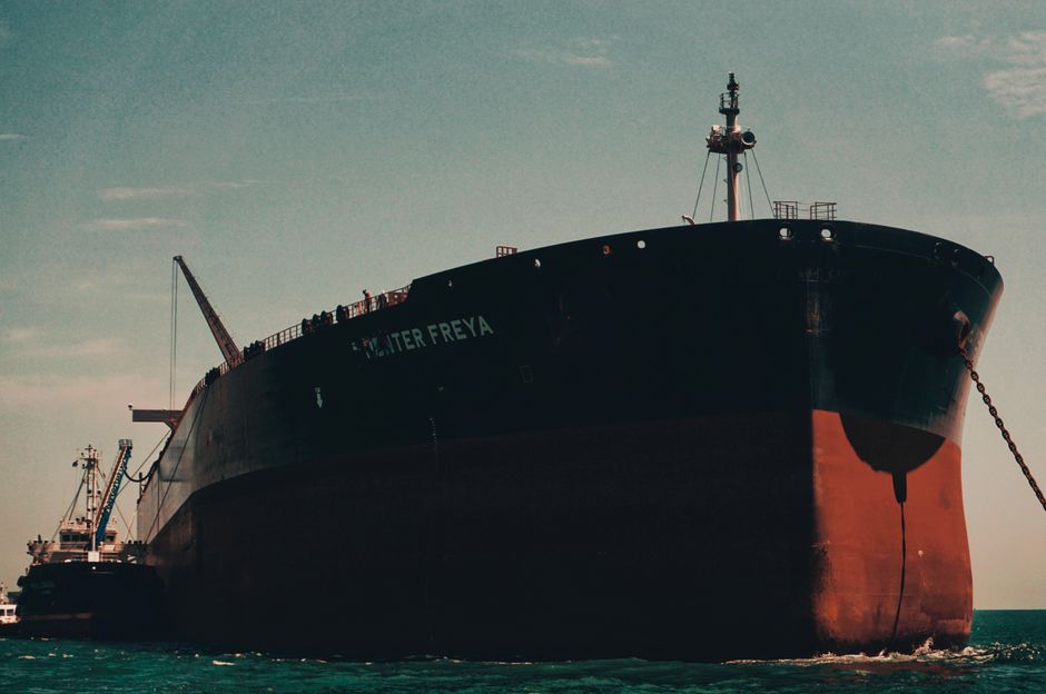 An oil tanker anchored near a busy maritime port