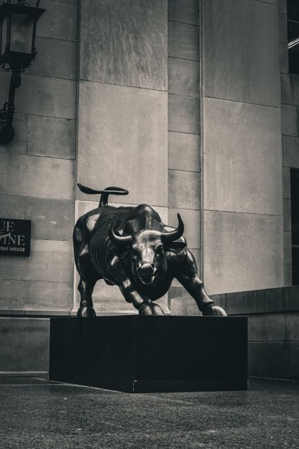 Black and white image of the Charging Bull statue in a cityscape