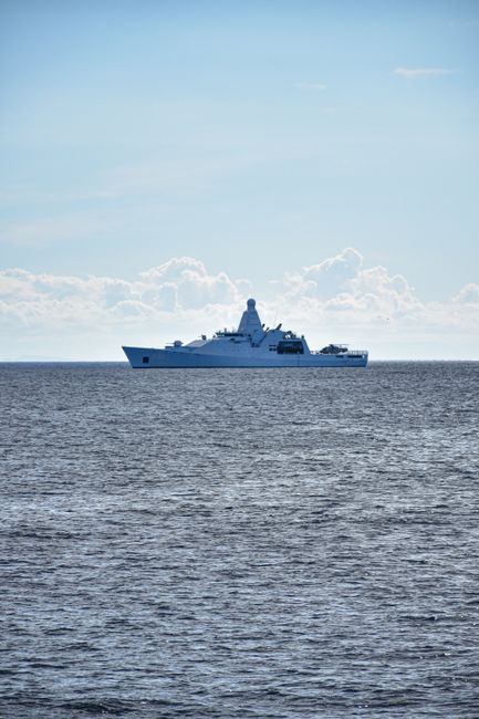 A naval warship sailing on a calm ocean under a clear sky