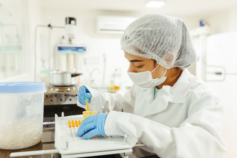 Scientist in protective equipment conducting an experiment in a pharmaceutical research laboratory