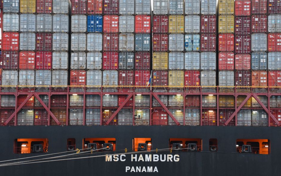 Stacked shipping containers mark the supply-chain exposure behind the market’s geopolitical energy shock.