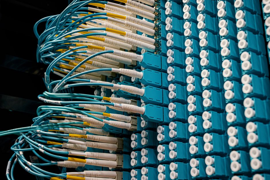 Fiber optic patch cables connected to a blue patch panel in a network data center