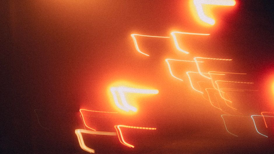 Vibrant orange light streaks captured through long exposure at night, creating dynamic abstract trails.
