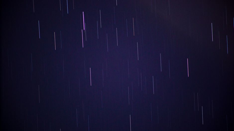 Long exposure of star trails creating circular patterns in a dark night sky.