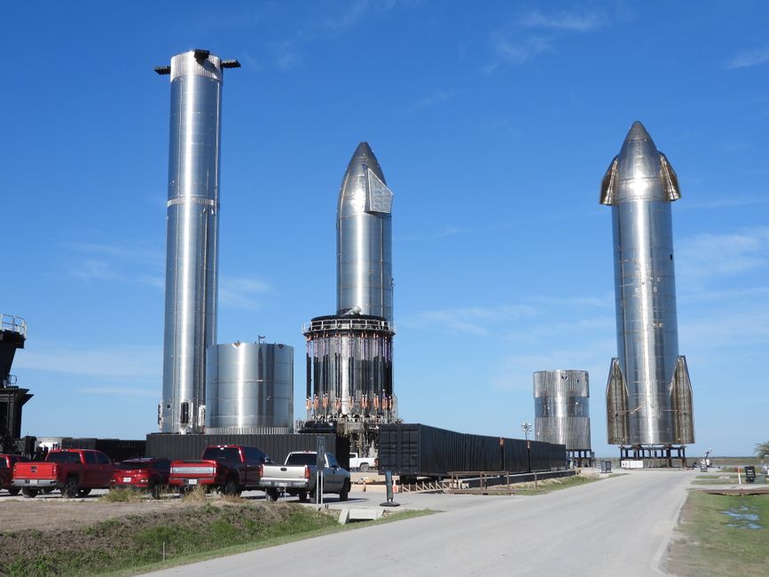 Tall rocket prototypes standing vertically at a launch site under a clear blue sky