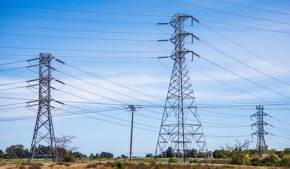 High voltage electric pylons carrying power across an open field.