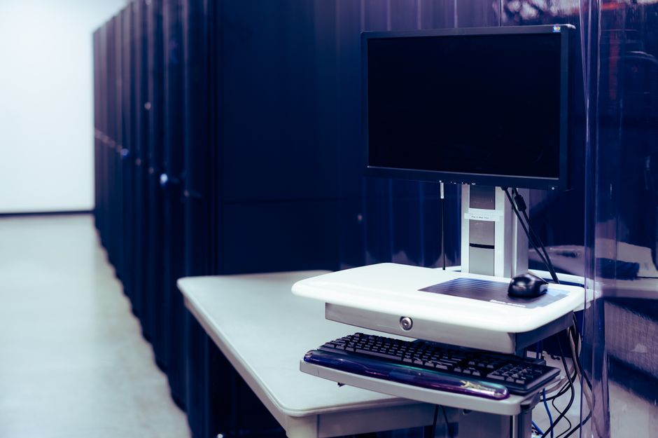 A data-center computer and server racks represent the capital intensity behind the AI buildout