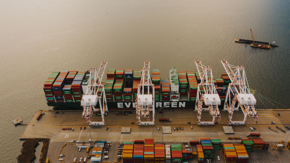 Cargo ship and cranes at a container terminal representing shipping and supply-chain disruption