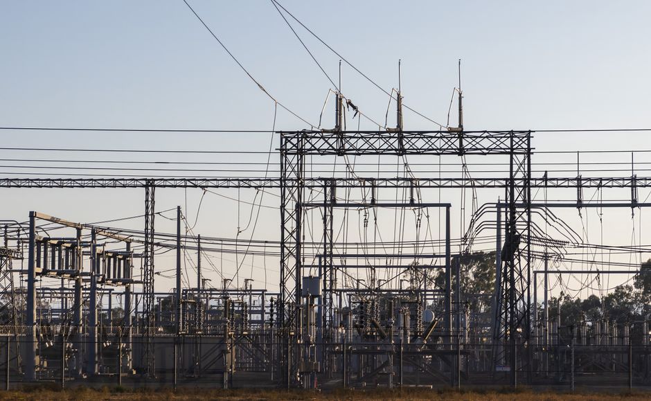 High-voltage electrical substation with steel structures and power lines at dawn, representing energy infrastructure and power generation.