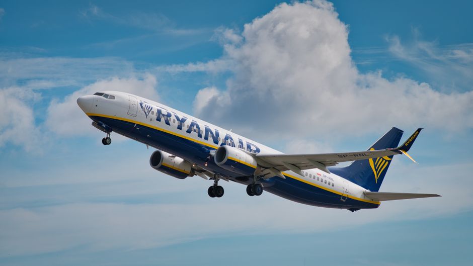 A commercial airliner ascends into a clear blue sky after takeoff.