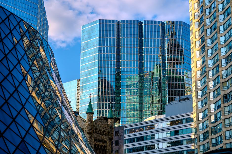 A vibrant cityscape featuring modern skyscrapers reflecting the blue sky and clouds in a financial district.