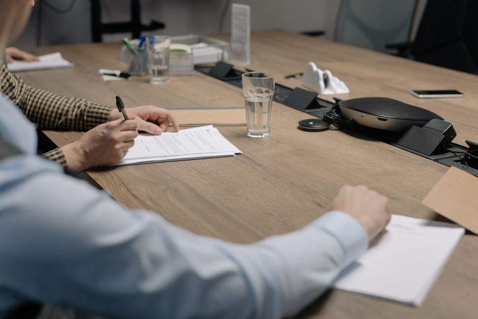 Professional setting of a business meeting with individuals signing documents on a conference table.