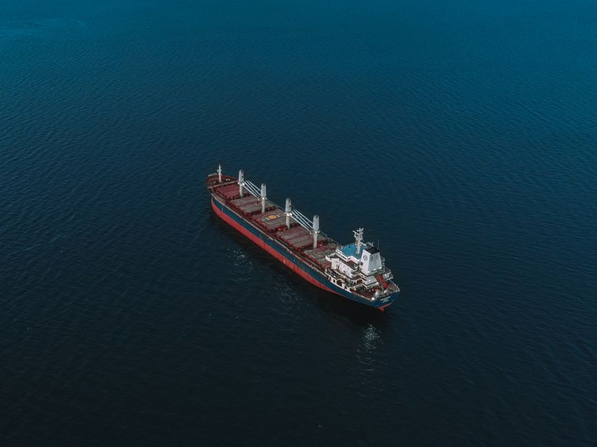 Aerial view of a cargo ship navigating the open ocean surrounded by deep blue water.