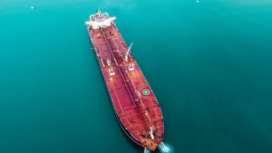 Aerial view of a large oil tanker vessel sailing through open ocean waters, photographed from directly above.