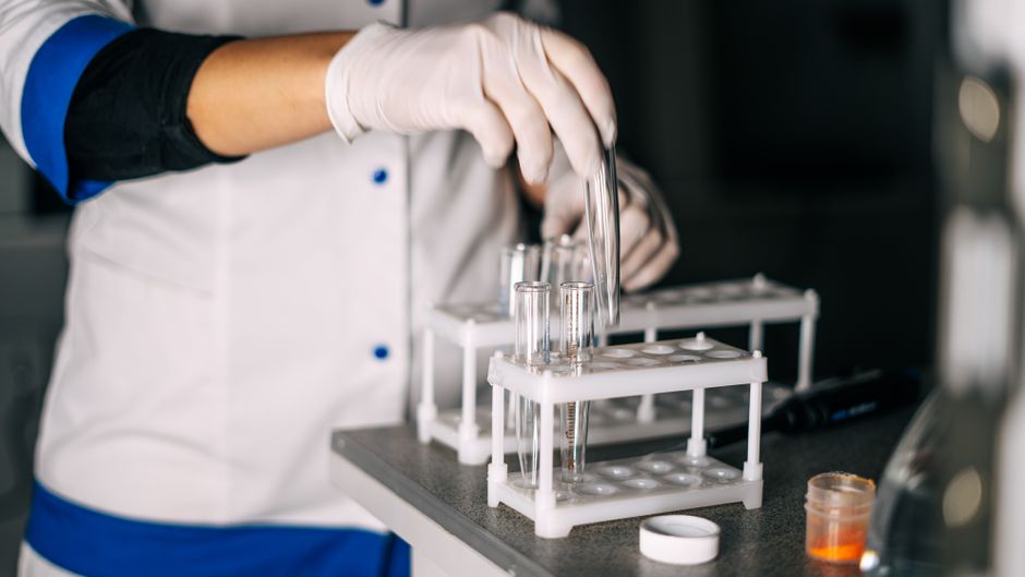 A scientist in a laboratory handling test tubes on a rack, representing biotech research and development.