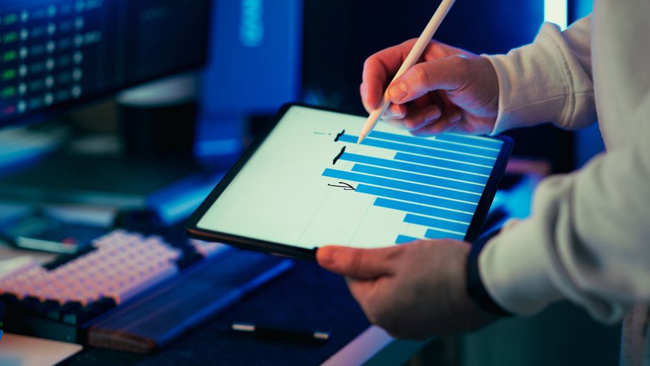 A business analyst reviews technology and market data on a tablet.