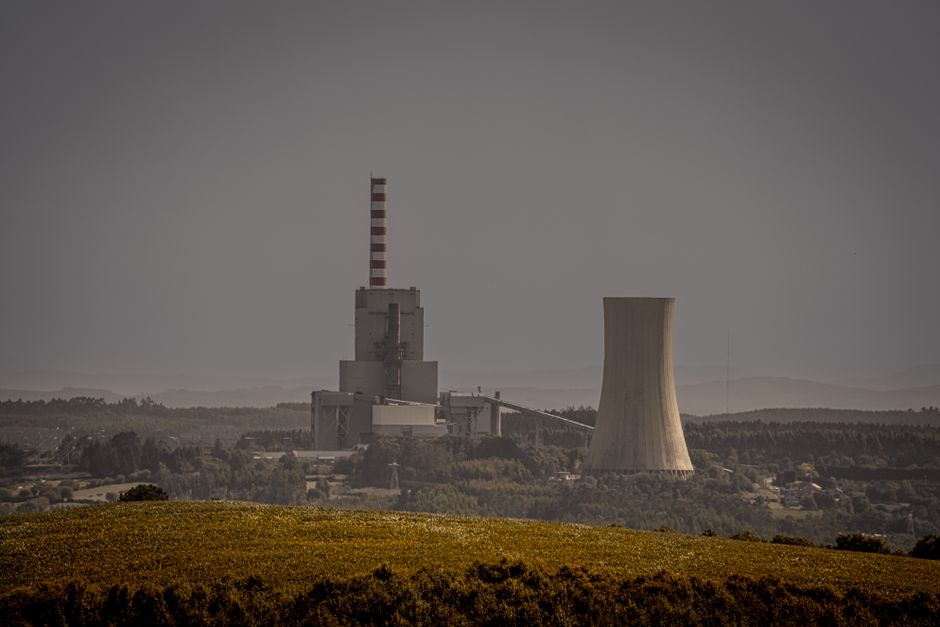 Distant view of a power plant with cooling towers in a valley, representing energy infrastructure