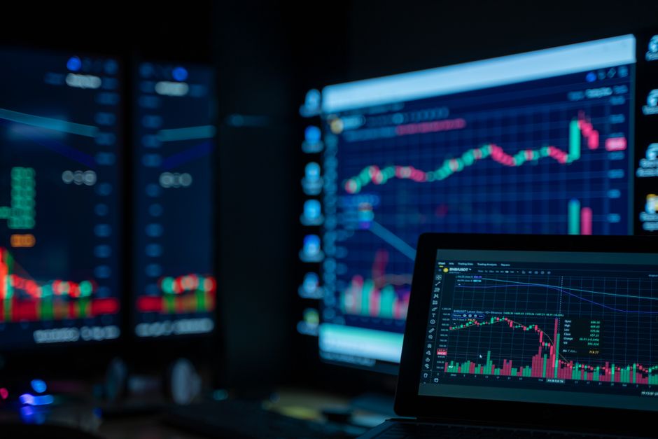 Stock market charts displayed on monitors in a trading environment
