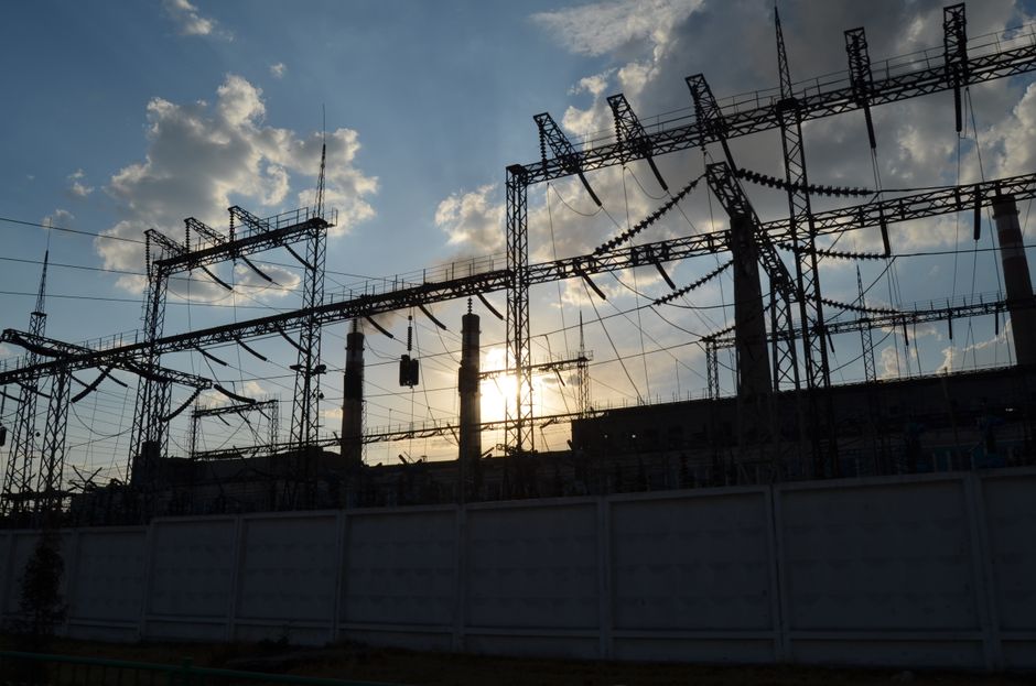 Electrical substation infrastructure silhouetted against a bright sky