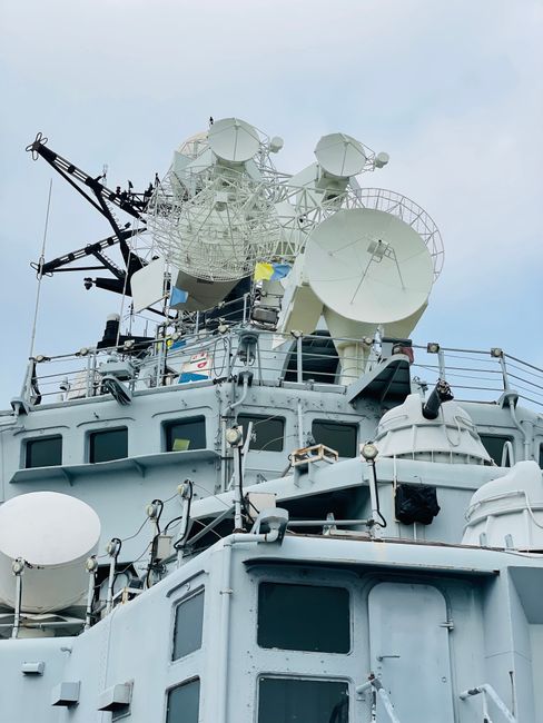 Close-up of a military battleship featuring satellite dishes under a blue sky.