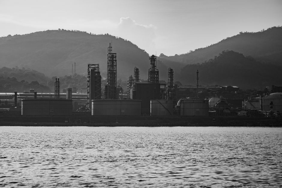 Industrial refinery silhouette against mountains, representing oil and energy infrastructure